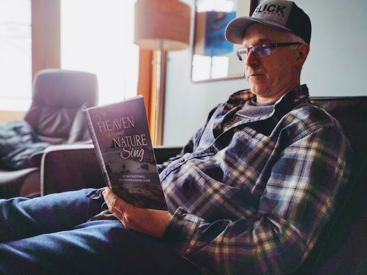 man reading "Heaven and Nature Sing" devotional book